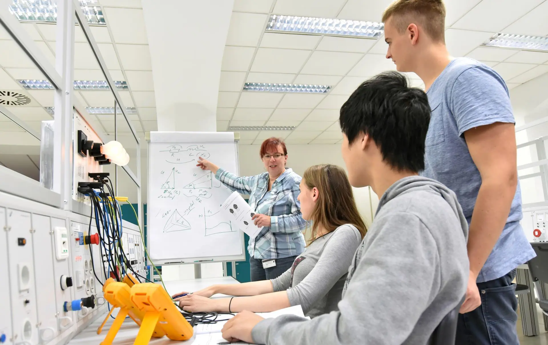 Für den Berufsschulunterricht wirst du von deinem Betrieb freigestellt; dafür gibt es aber auch Pflichten. Im Bild: Berufsschullehrerin erklärt einer Gruppe elektrotechnische Zusammenhänge.