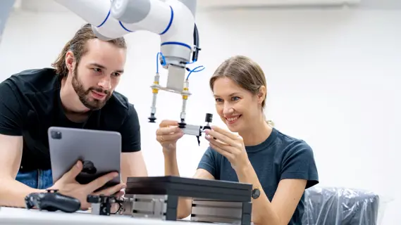 Zwei Nachwuchstalente bei technischen Arbeiten mit einem Cobot.