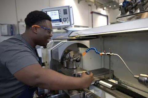 Junger Zerspanungsmechaniker bei der Arbeit an der Maschine