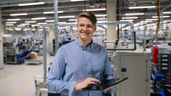 Junger Fachinformatiker mit Tablet in der Werkhalle.