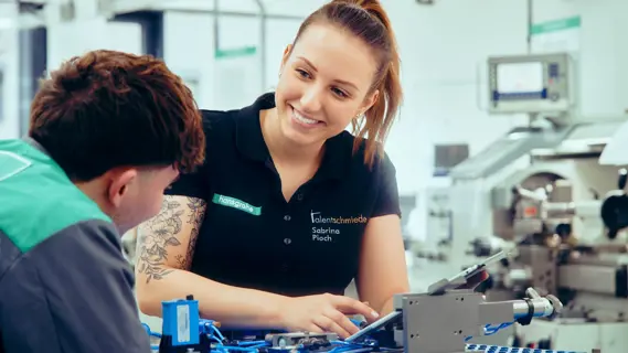 Duale Studentin bei technischen Arbeiten mit einem jungen Kollegen.