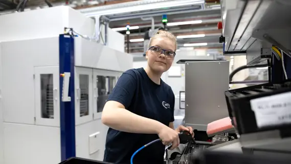 Junge Fluggerätmechanikerin am Arbeitsplatz in der Werkhalle.