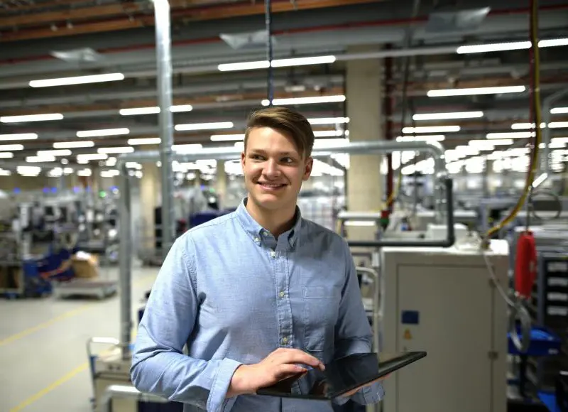 Junger Fachinformatiker mit Tablet in der Werkhalle